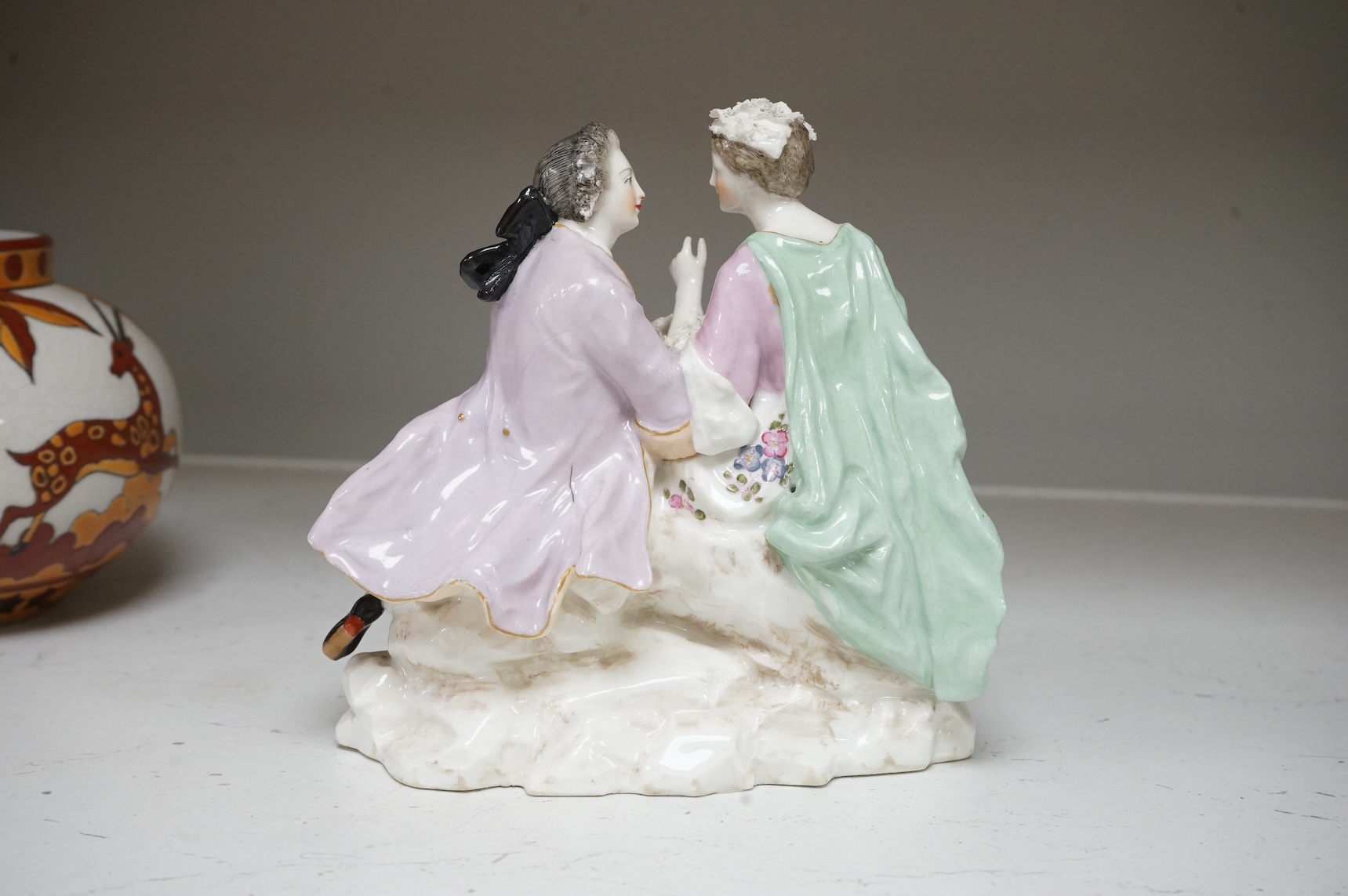 A German porcelain group of a seated courting couple, 16.5cm high